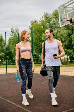 Spor giyim sektöründe kararlı bir erkek ve kadın basketbol sahasında birlikte yürürler.