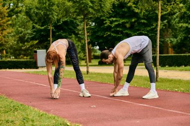 Spor giyimli bir kadın, bir pistte kişisel antrenörüyle egzersiz yapıyor, azim ve motivasyon gösteriyor..