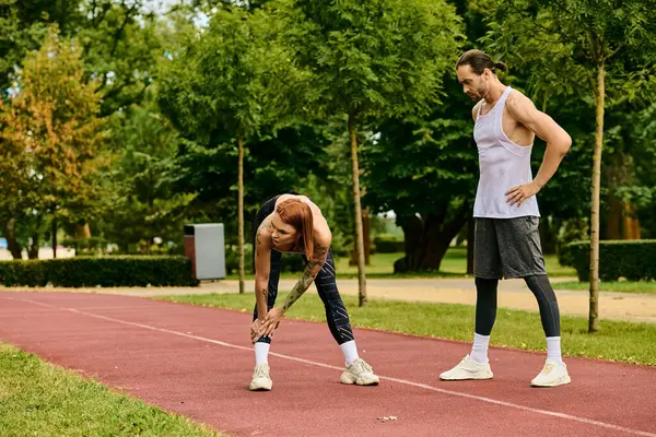 stock image A man and woman in sportswear stand on a track, exercising together with determination and motivation.