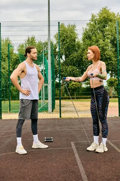 スポーツウェアと彼女のパーソナルトレーナーの女性は 一緒に運動することを決意し 意欲的にテニスコートに立っています — ストック写真