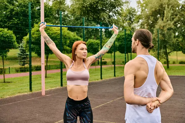 Spor kıyafetleri giymiş bir kadın ve bir erkek, mahkemede birlikte antrenman yapıyorlar.