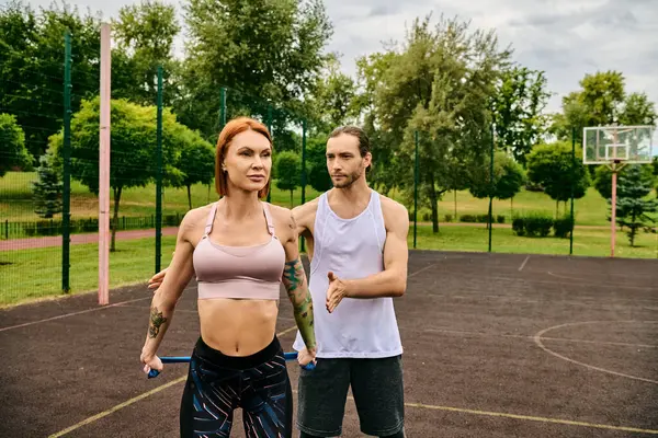 stock image A man and a woman, in sportswear, motivate each other while exercising on a court with determination and teamwork.