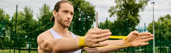 stock image A man holds a vibrant yellow object in his hands, resistance band training