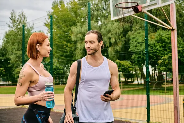 stock image A man and woman in sportswear exercise outdoors, showcasing determination and motivation.