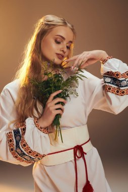 Beyaz elbiseli genç bir kadın peri ve fantezi stüdyosunda bir buket çiçek tutuyor..