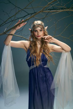 Elf prensesi gibi giyinmiş genç bir kadın. Stüdyoda başında taç olan mavi bir elbise giyiyor..