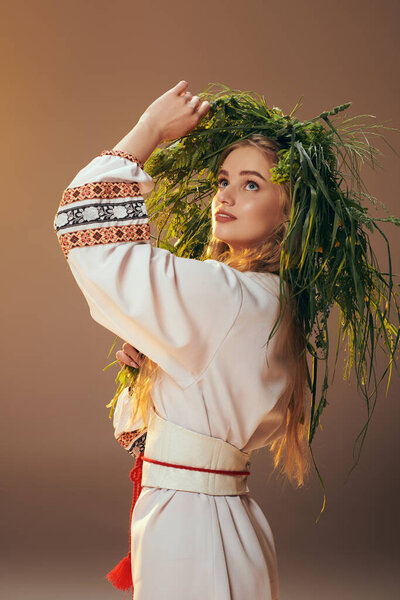 A young woman in traditional attire wears an ornate wreath in a studio setting, embodying fairy and fantasy elements.