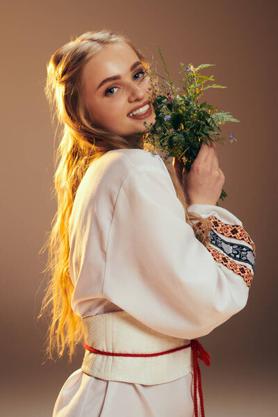 A young maiden in a white dress delicately holds a graceful flower in a serene studio setting.