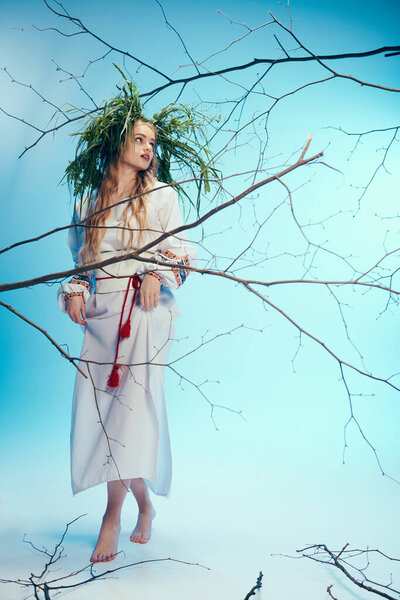 Young mavka in ornate white dress delicately balances a plant on her head in a whimsical studio setting.