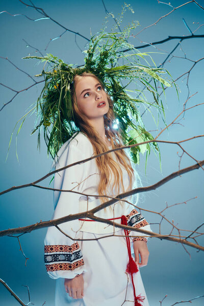 A young mavka stands gracefully in front of a tree, dressed in a traditional outfit with an ornate wreath on her head.