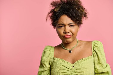 A stylish African American woman in a yellow top poses on a vibrant backdrop. clipart