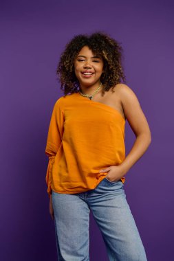 Canlı arkaplanda turuncu bluzlu poz veren şık bir kadın..