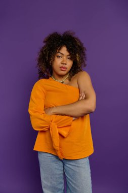 Güçlü Afro-Amerikan kadın şık giyinmiş kollarını çapraz pozlarla mor arkaplanda poz veriyor..