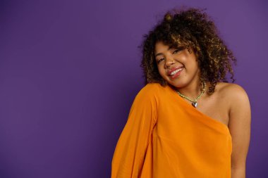 Çarpıcı Afro-Amerikalı kadın canlı turuncu elbisesiyle poz veriyor..