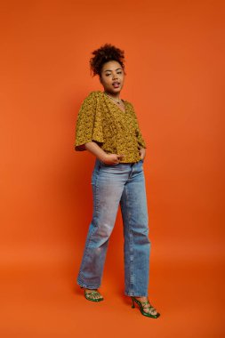 African American woman in stylish attire poses against vibrant orange backdrop. clipart