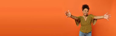 Man extends arms in front of vibrant orange background. clipart
