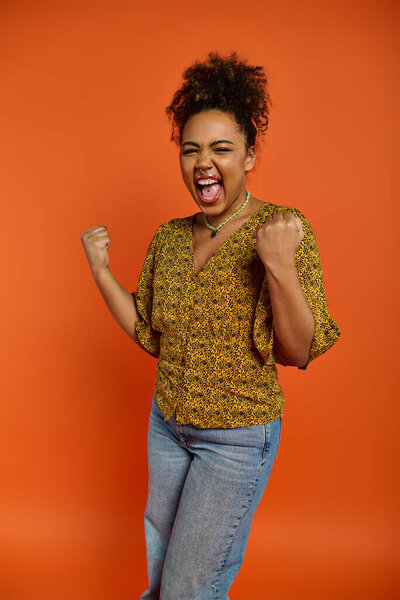 Красивая афроамериканка в стильной одежде с взволнованным выражением лица на ярком фоне.