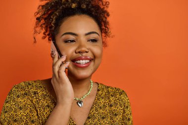 Cep telefonuyla konuşurken gülümseyen şık giyinmiş Afrikalı Amerikalı kadın..