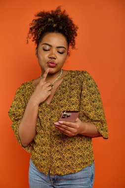 Güzel bir Afro-Amerikalı kadın şık giyinmiş cep telefonuna bakıyor..