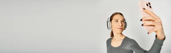 stock image A sporty young woman in active wear holding a cell phone up to her face, engaged in a phone call.