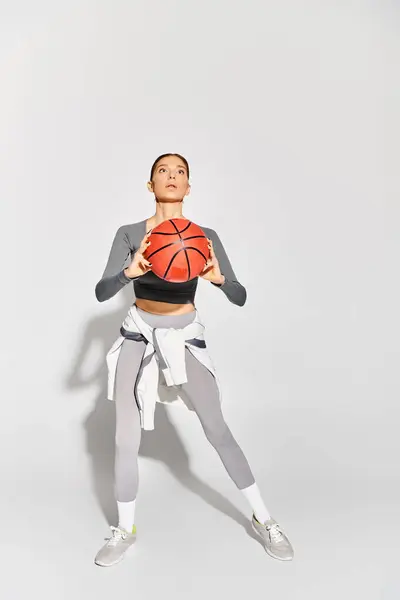 Спортивная Молодая Женщина Элегантно Держит Баскетбол Правой Руке Сером Фоне — стоковое фото