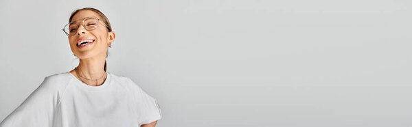 A young woman wearing glasses and a white shirt poses against a grey background, exuding a sense of calm and confidence.