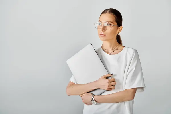 stock image Young woman in glasses holding laptop, deep in thought, ready to jot down her ideas and inspirations.