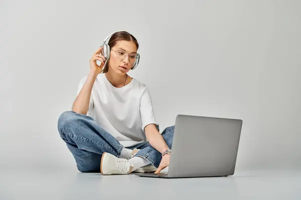 Młoda Kobieta Białej Koszulce Okularach Siedzi Podłodze Laptopem Słuchawkami Pochłonięta — Zdjęcie stockowe