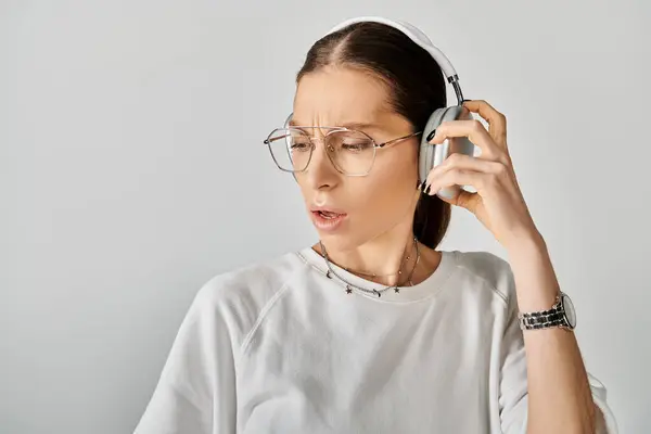 stock image A young woman in a white t-shirt and glasses listens music