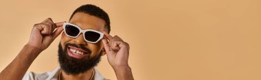 A man with a stylish beard wearing white sunglasses, exuding a cool and confident vibe as he gazes into the distance. clipart