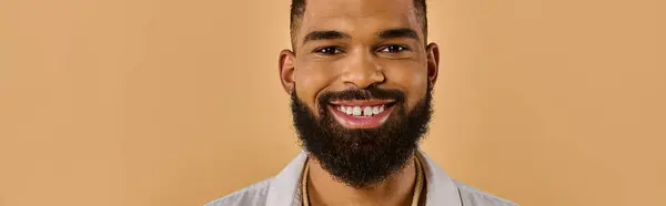 stock image A man with a full, bushy beard grins warmly at the camera, his eyes sparkling with happiness and a hint of mischief.