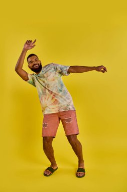 A man wearing a vibrant tie dye shirt paired with pink shorts, exuding a laid-back and colorful aura in his outfit choice. clipart