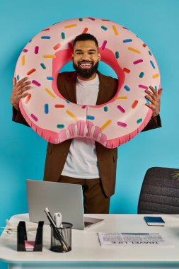 Bir adam şakacı bir şekilde kocaman bir donutu gözünün önünde tutuyor, yaramaz bir gülümsemeyle delikten bakıyor..