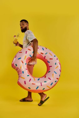 A man joyfully holds a gigantic donut in one hand and a glass of beer in the other, showcasing a unique and delicious pairing of treats. clipart