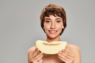 Woman hides behind a piece of fruit. clipart