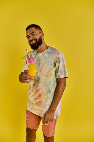 A stylish man in a tie dye shirt holding a drink, adding a pop of color to the scene with his vibrant outfit.