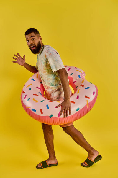 A man stands holding a massive doughnut in his right hand, showcasing the impressive size of the sweet treat.