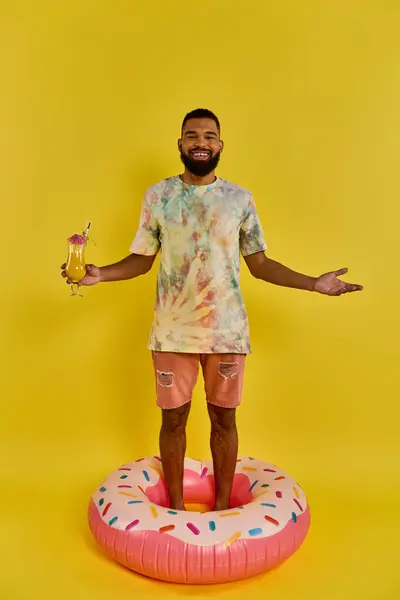 一个男人自信地在一个巨大的甜甜圈之上保持平衡 手握酒杯 在一个超现实和异想天开的场景中畅饮 — 图库照片