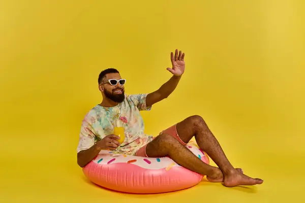 stock image A man is peacefully seated atop a large inflatable donut, gently floating on calm waters, enjoying the serene surroundings.