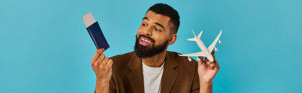 A man holds a small model airplane in one hand and a passport in the other, symbolizing travel aspirations and adventure readiness.