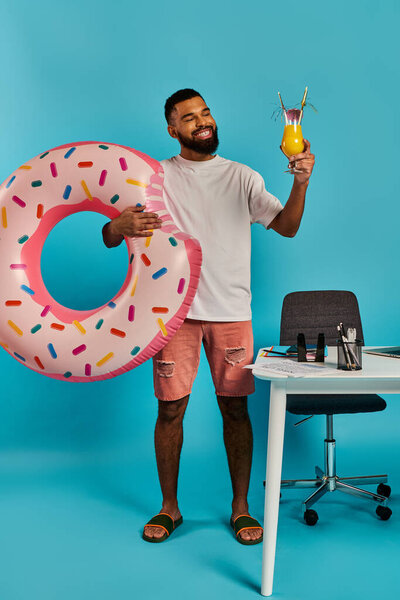 A man is joyfully holding a drink and a massive donut in his hands, clearly enjoying his indulgent treats.