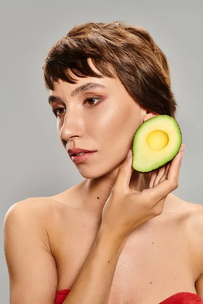 Young Woman Delicately Holds Avocado Her Hand Vibrant Backdrop — Stock Photo, Image