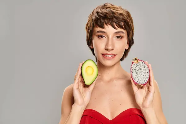 Young Woman Delicately Holds Avocado Slice Vibrant Backdrop — Stock Photo, Image