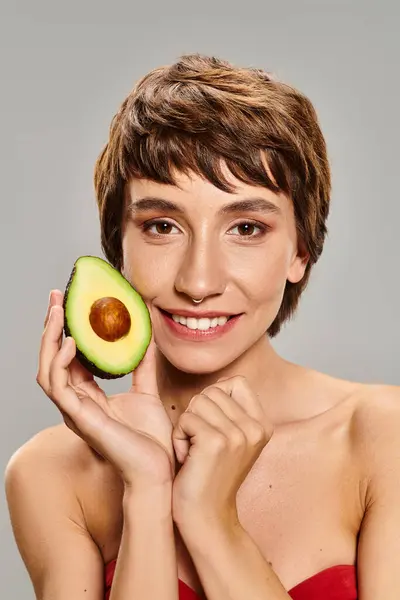 Jonge Vrouw Houden Avocado Voor Haar Gezicht — Stockfoto