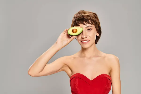 Jonge Vrouw Een Rode Jurk Poseert Met Een Avocado Tegen — Stockfoto