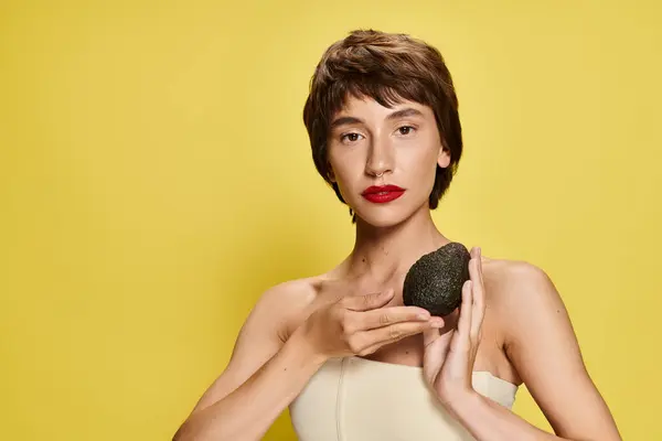 stock image Young woman in white dress holding avocado.