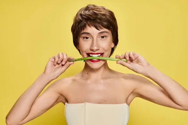 Young Woman Holds Asparagus Mouth Vibrant Backdrop — Stok fotoğraf