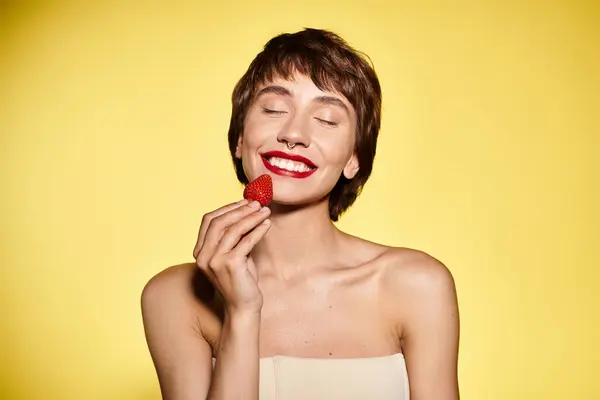 Woman Delicately Holds Strawberry Her Face Vivid Backdrop — Stock Photo, Image