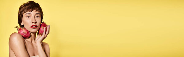 Женщина игриво держит два драконьих фрукта перед лицом.