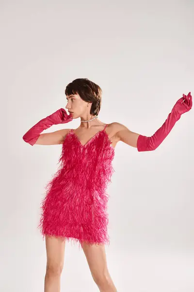一个时髦的年轻女子穿着华丽的红色衣服 戴着粉色手套 衬托着充满活力的背景 — 图库照片
